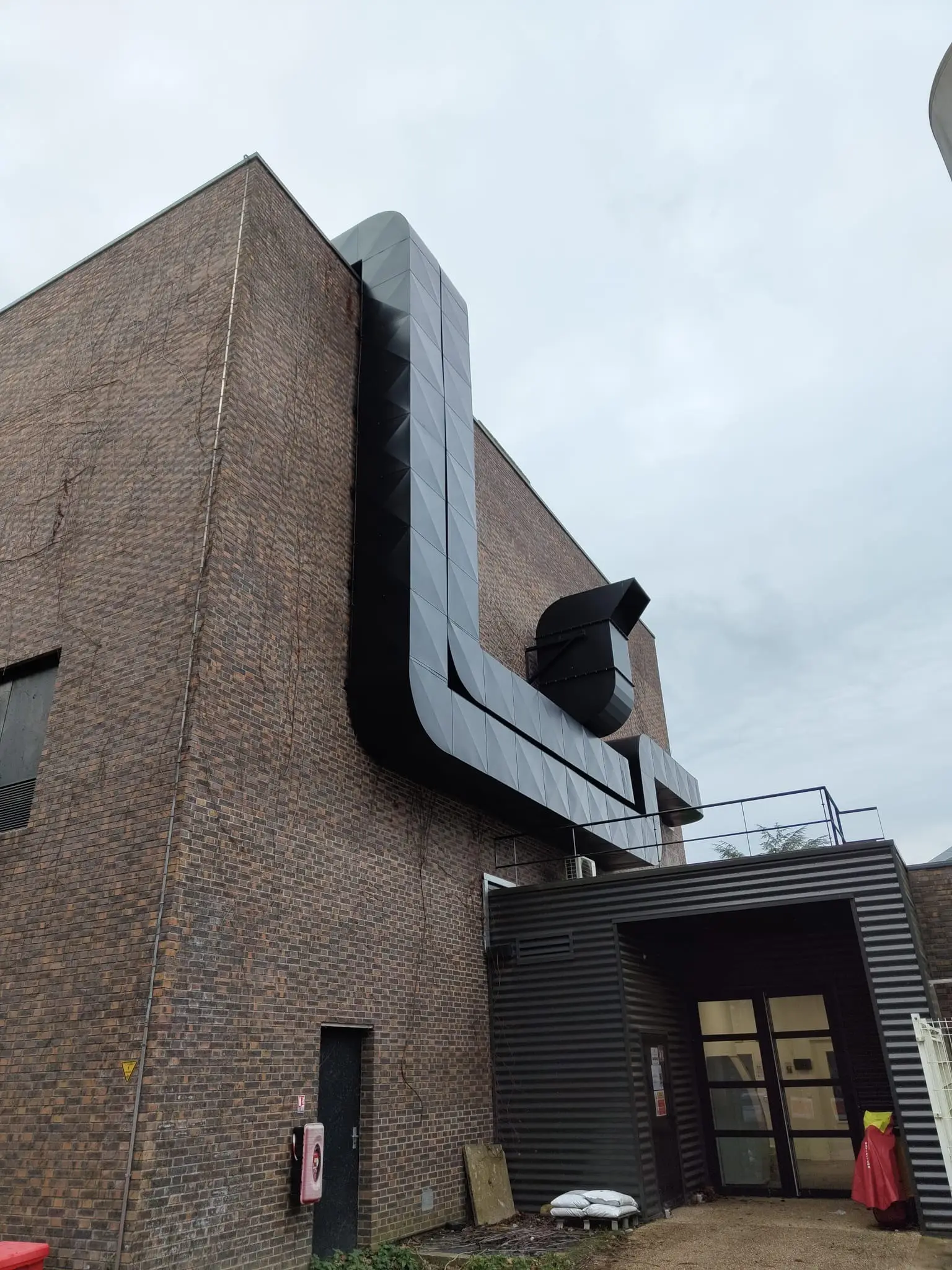Gaines extérieures calorifugées en tôle isoxal noire RAL 9005 le long d’un bâtiment industriel des Yvelines